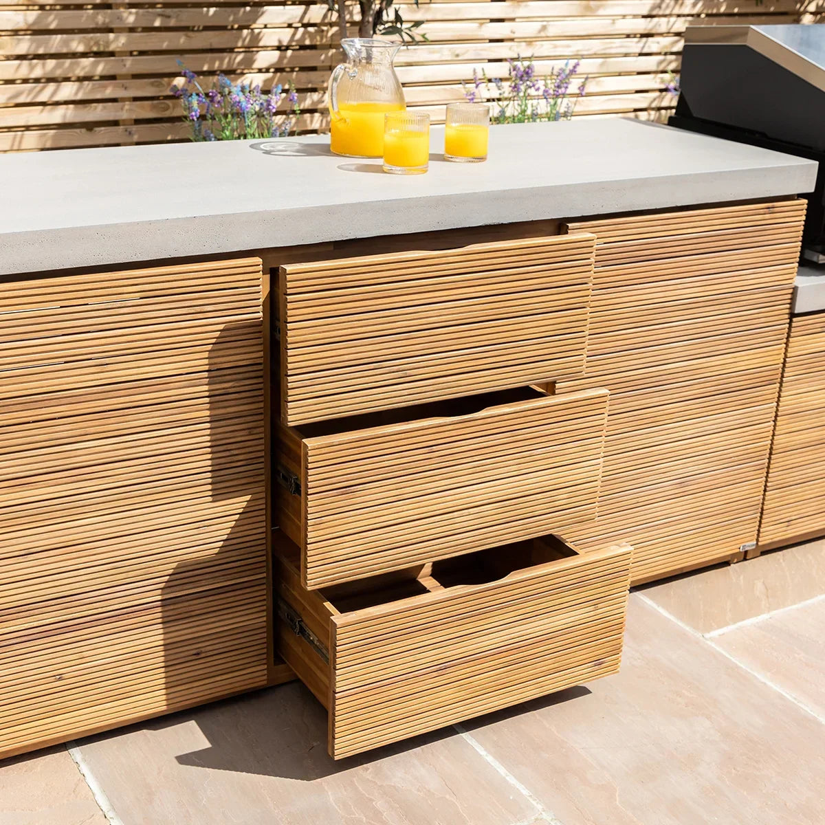 Outdoor kitchen unit with ribbed wood drawers and concrete countertop, orange juice on top