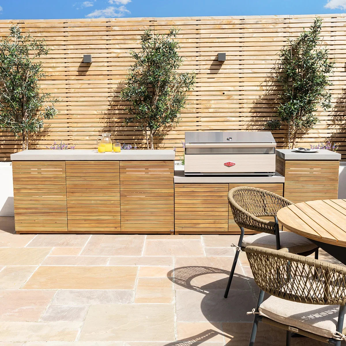 Outdoor kitchen unit with wood cabinets, stainless steel barbecue and patio dining chairs