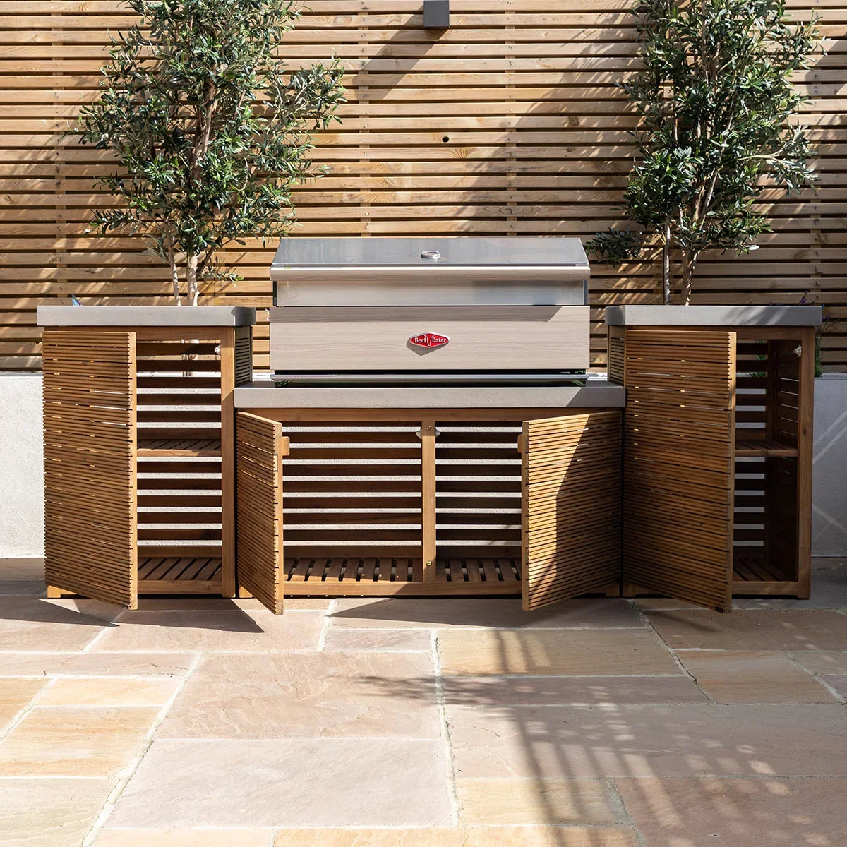 Outdoor wooden kitchen with built-in stainless steel barbecue grill and open slatted storage
