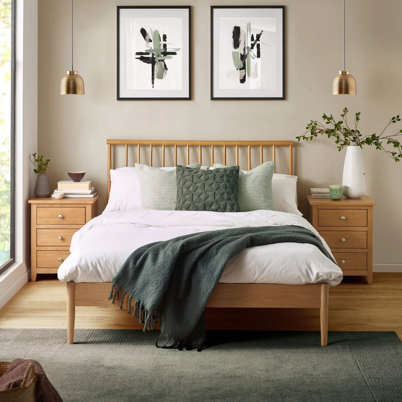 Oak wooden bed frame with white bedding and green cushions in modern bedroom setting
