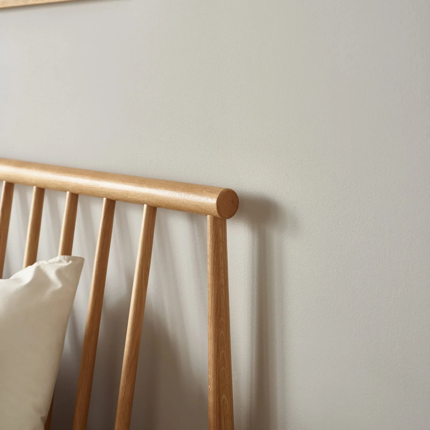 Oak wooden bed frame headboard with vertical slats against light wall