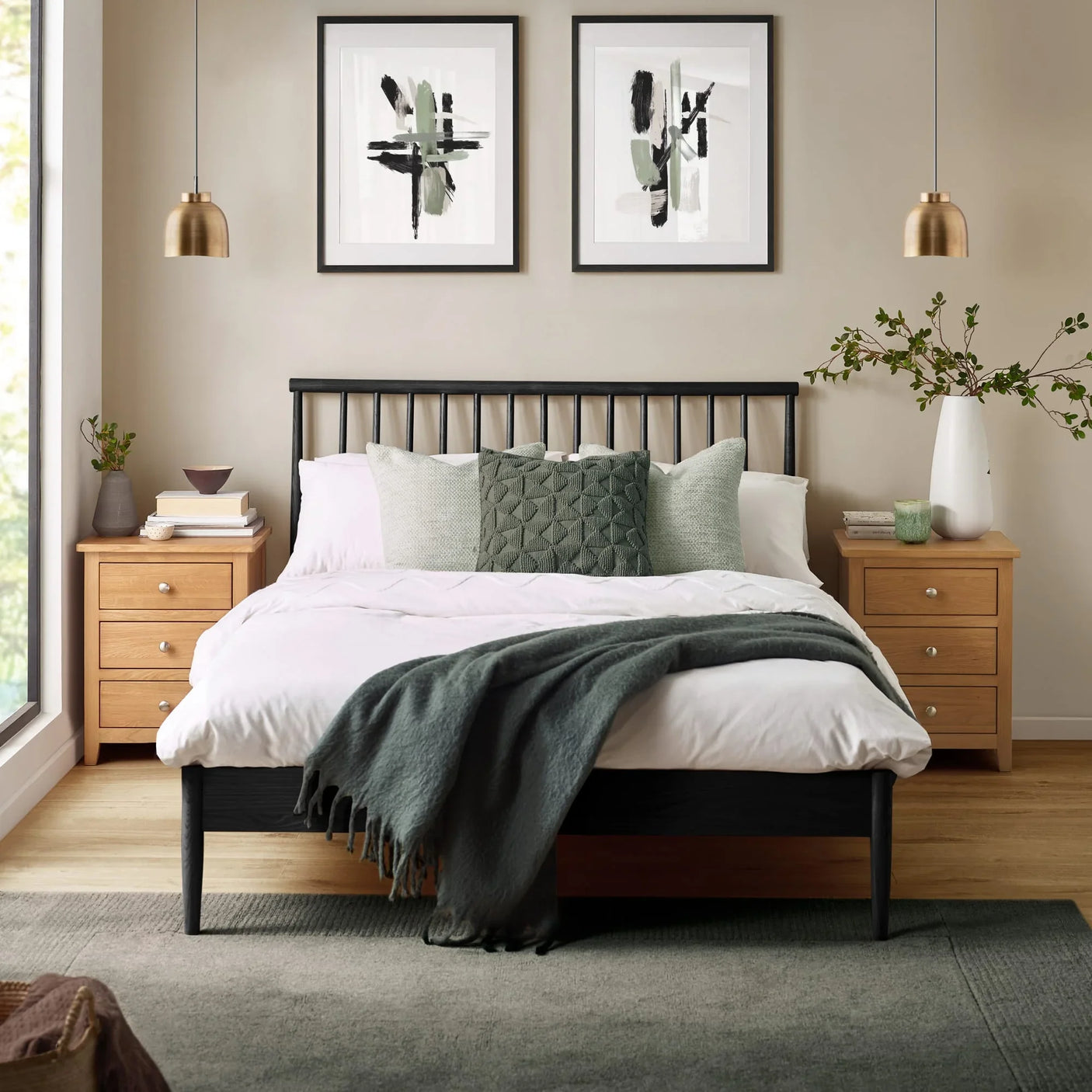Black wooden bed frame with white bedding, sage pillows, and oak bedside tables in modern bedroom