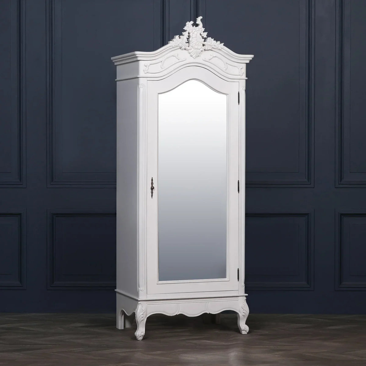White mirrored wardrobe with ornate detailing and curved legs against navy paneled wall