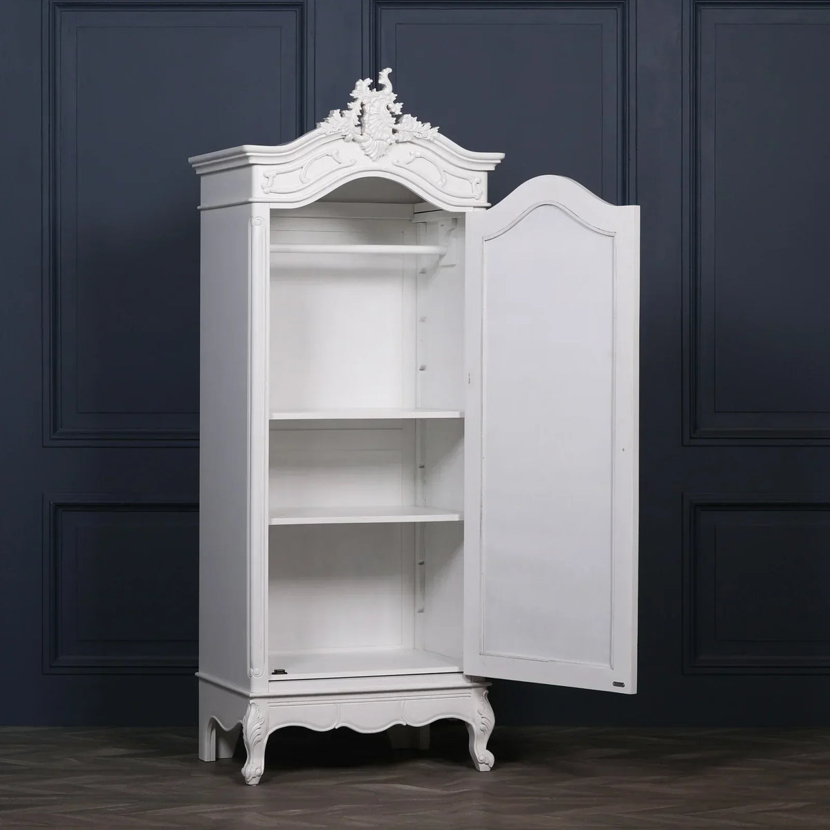 White wooden wardrobe with ornate carved detailing and open door showing shelves
