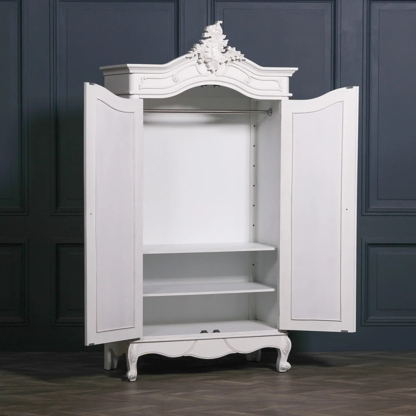White wooden wardrobe with ornate crest, open doors, shelves and hanging rail