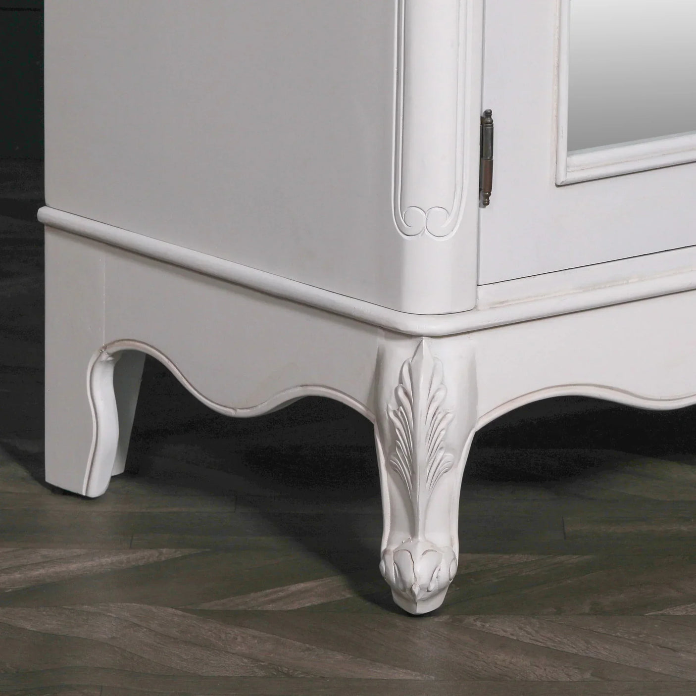 White wooden cabinet with carved decorative leg and mirrored door corner view