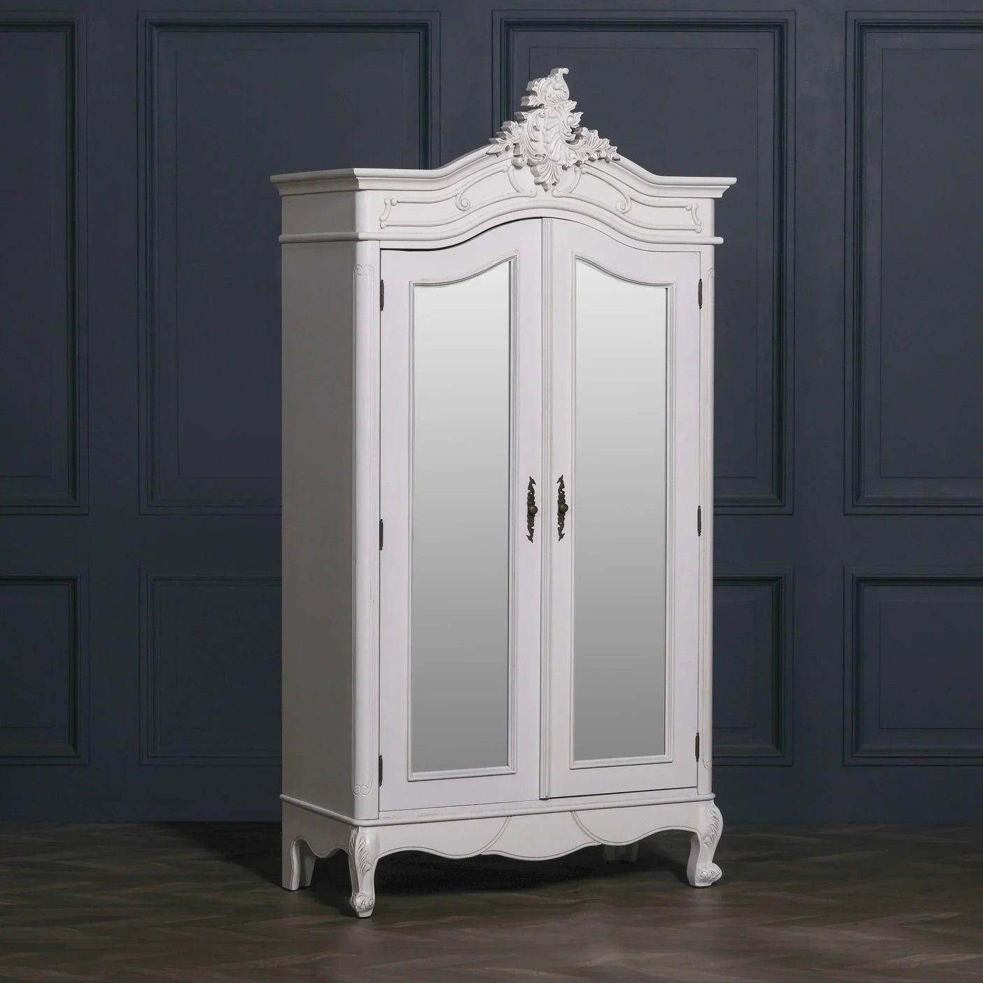 White mirrored wardrobe with ornate detailing and curved legs against dark panelled wall