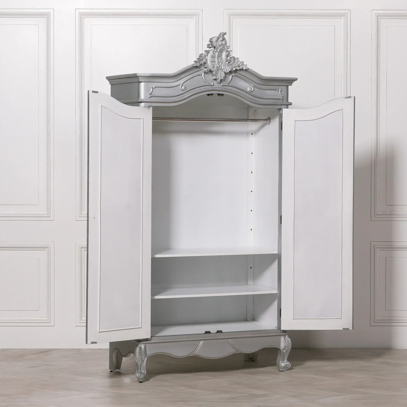 White and silver wardrobe armoire with ornate top and open doors showing shelves and rail