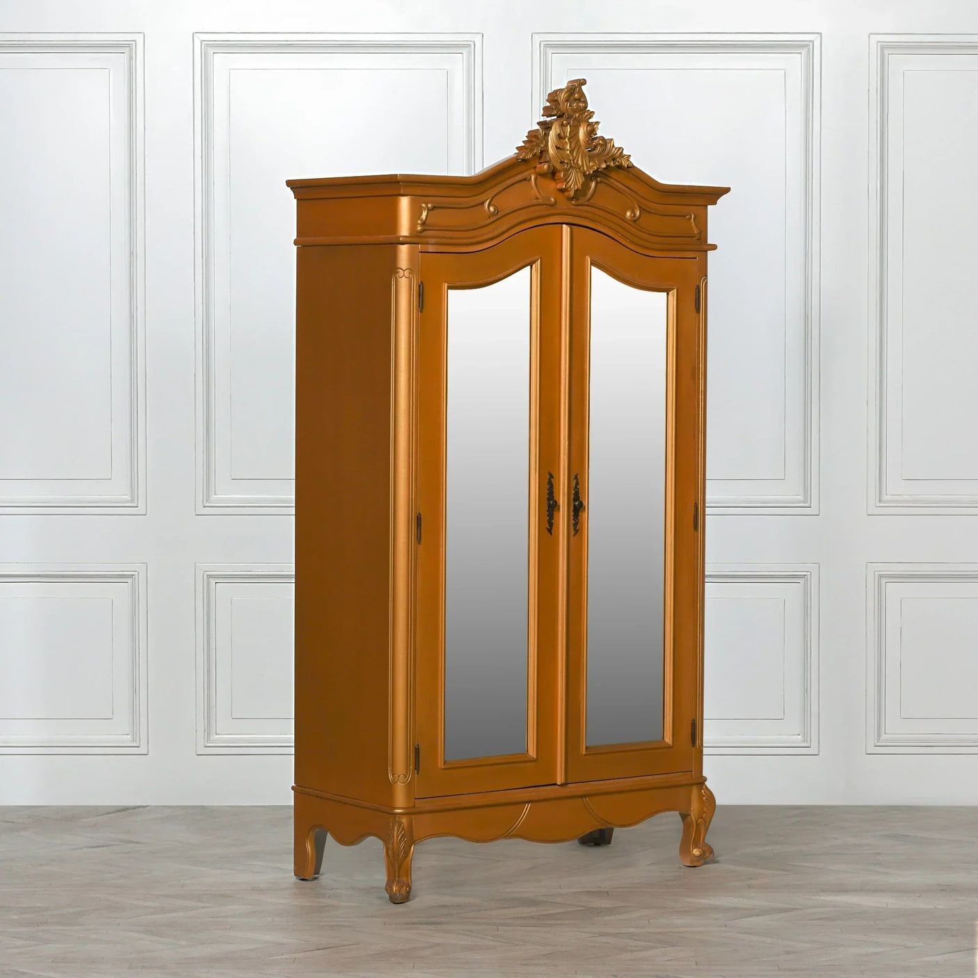 Gold mirrored wardrobe with ornate crest and double doors in classic styled room