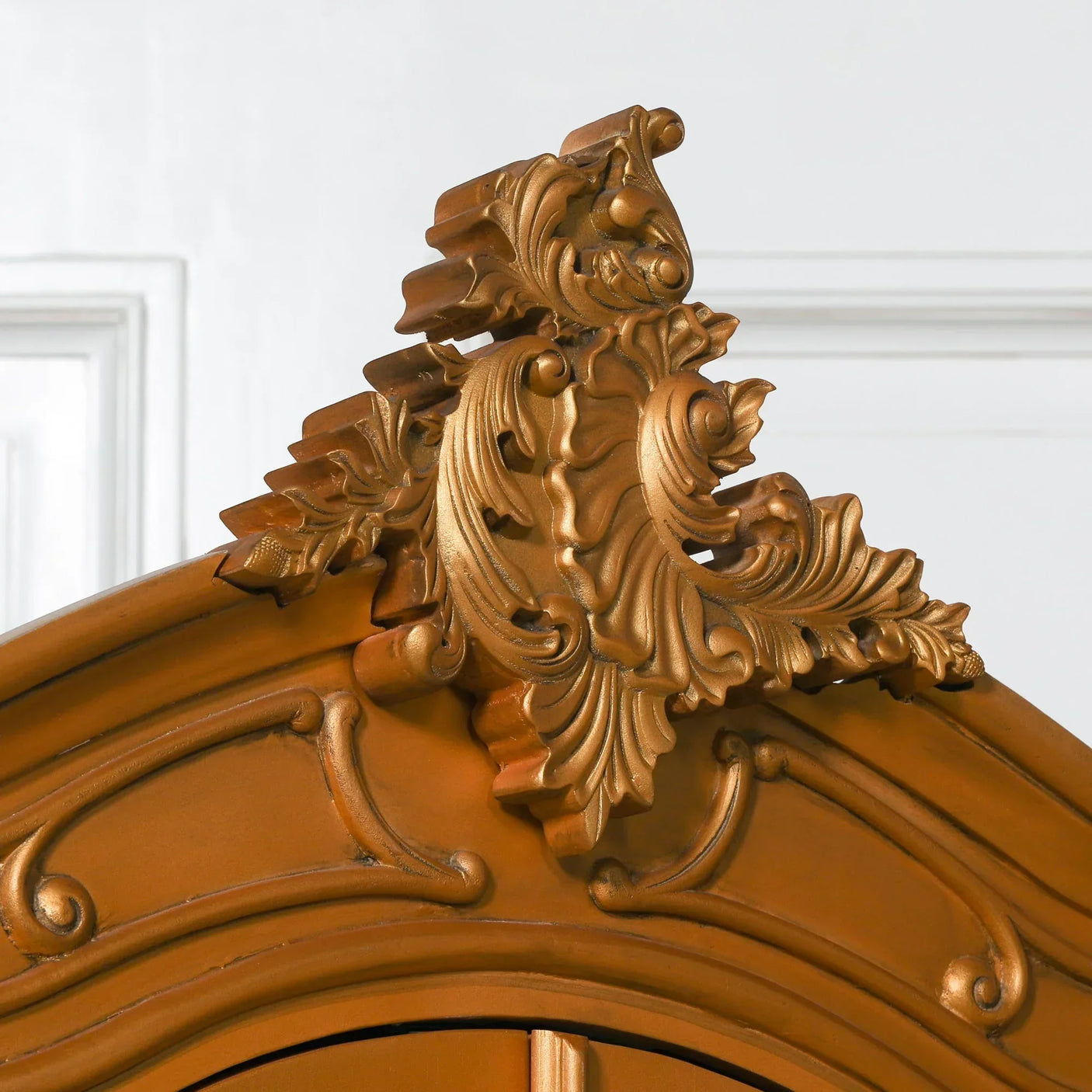 Ornate wood wardrobe top detail with carved decorative moulding and gold finish