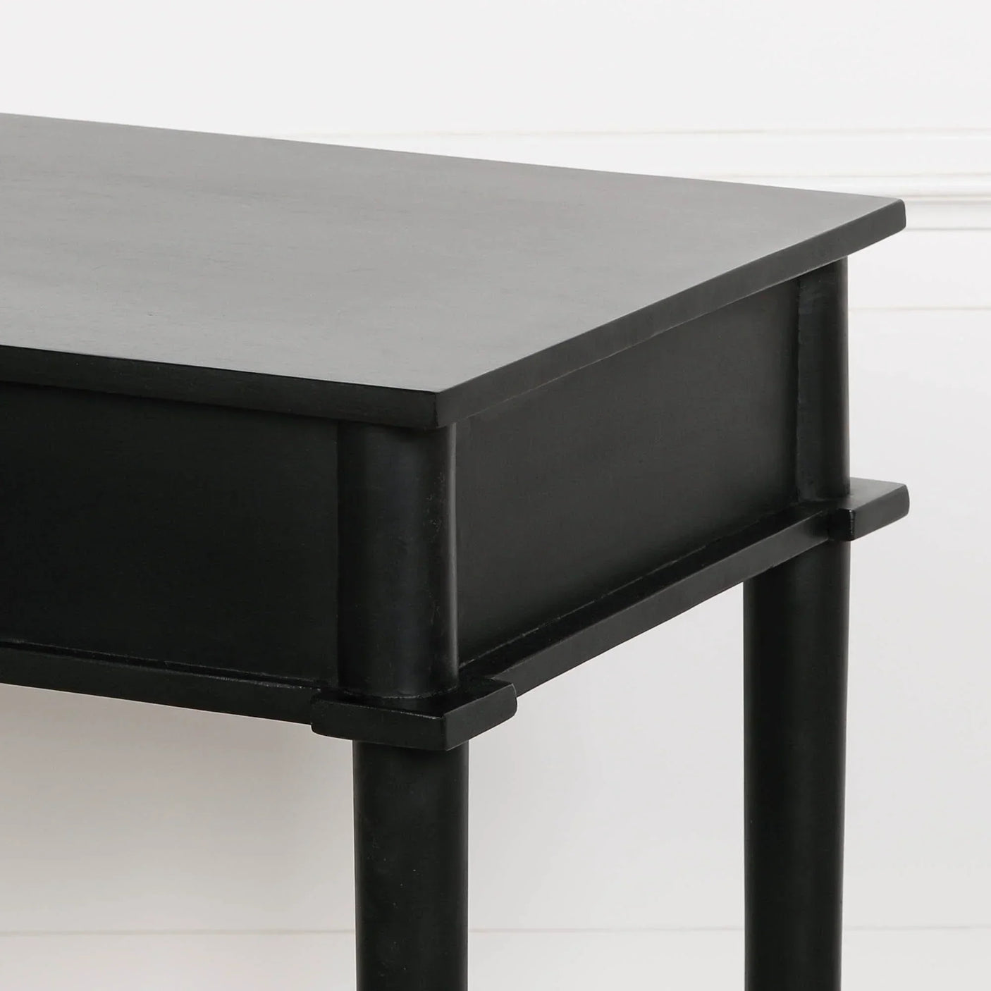 Matte black side table with square top and round legs against a white wall