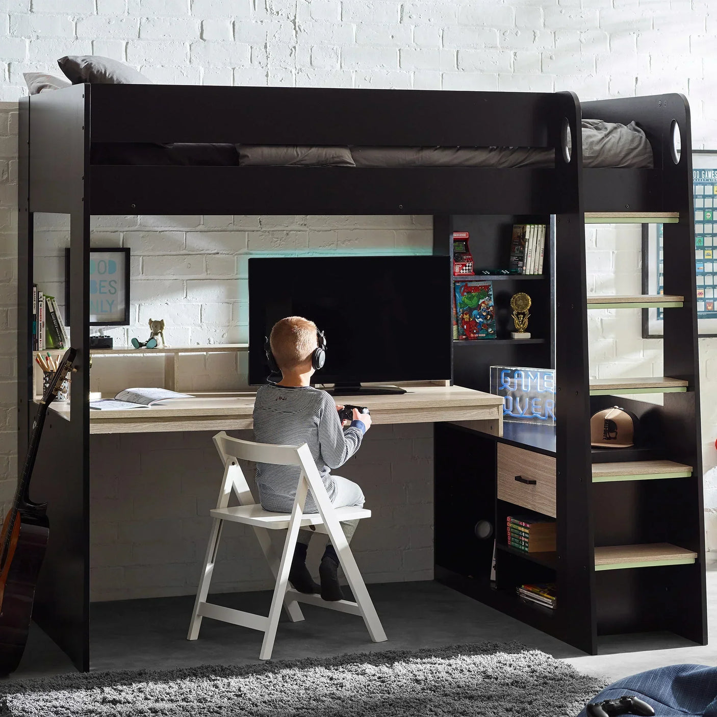 Black and pale wood gaming highsleeper bed with desk, shelves, and child seated at monitor