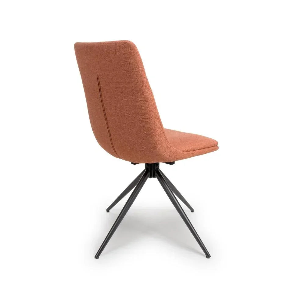 Rust fabric dining chair with angled black metal legs, rear side view
