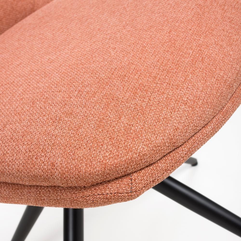 Closeup of orange fabric dining chair seat with black metal legs