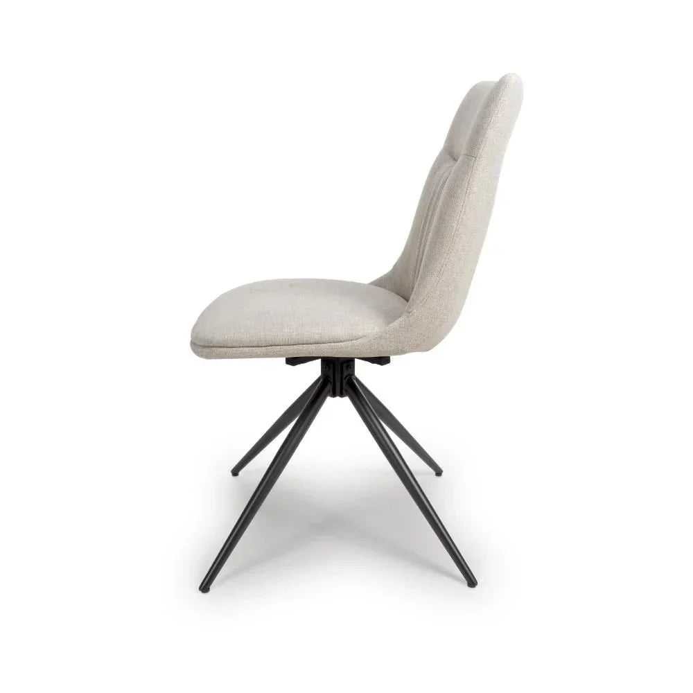 Beige fabric dining chair with padded seat and black metal legs, side profile view