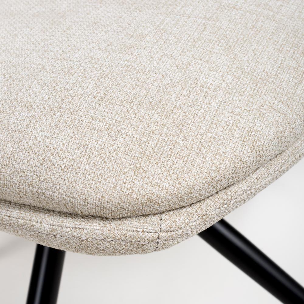 Beige fabric dining chair seat with black metal legs close-up