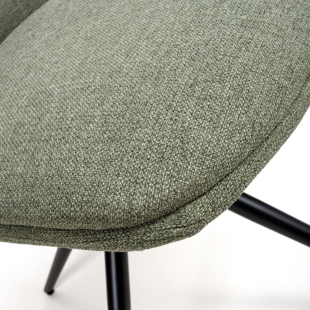 Green fabric dining chair seat with black legs, close-up on upholstery texture