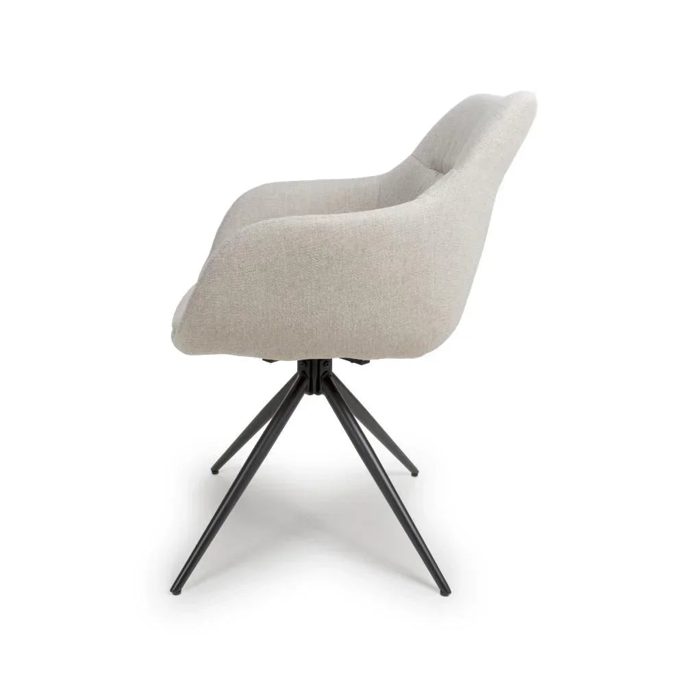 Beige fabric dining chair with curved backrest and black metal legs, side angle view