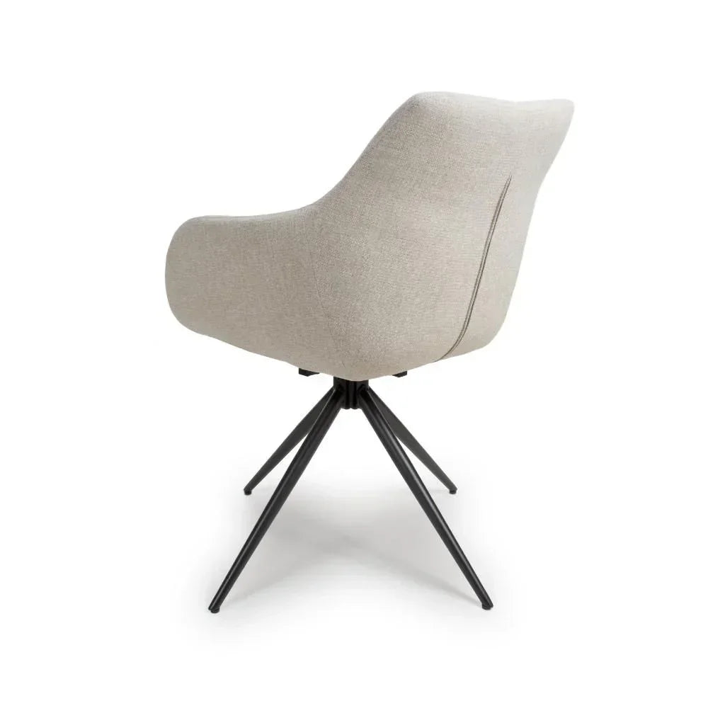 Beige fabric dining chair with curved back and black metal legs, rear angle view