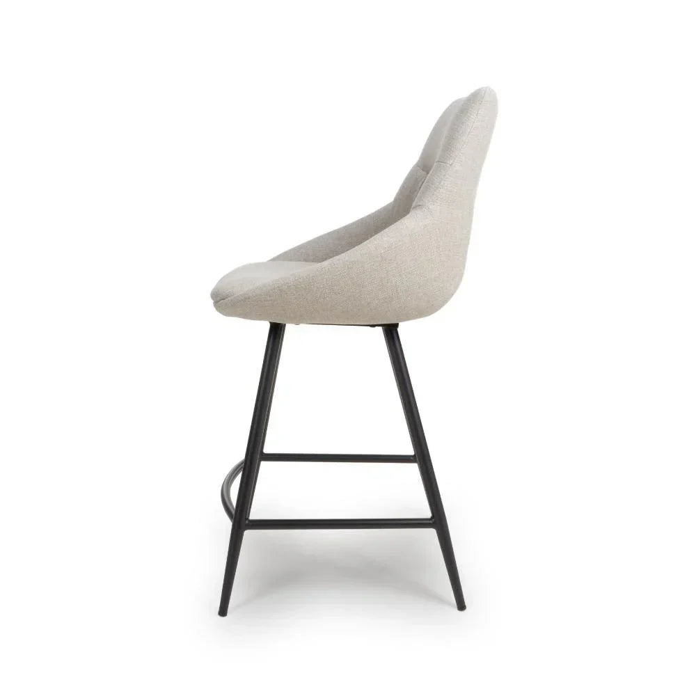 Side view of beige upholstered bar stool with black legs and footrest