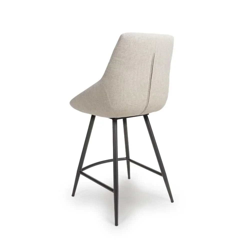 Beige fabric bar stool with curved backrest and black metal legs, rear view