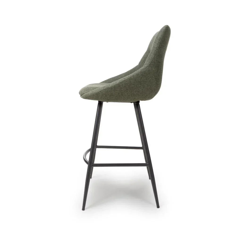 Green fabric bar stool with high curved back and black metal legs, side profile view