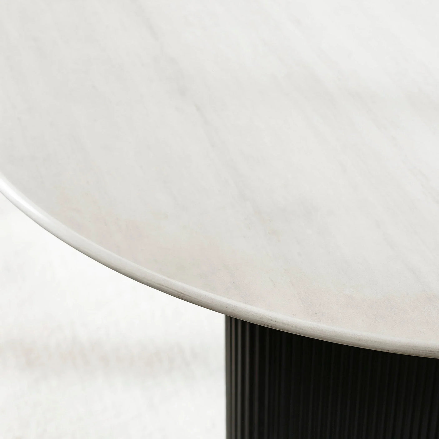Closeup of oval marble dining table top with black fluted base