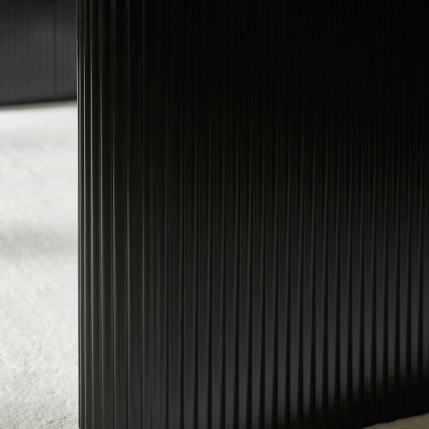 Close-up of black ribbed furniture panel on light carpeted floor