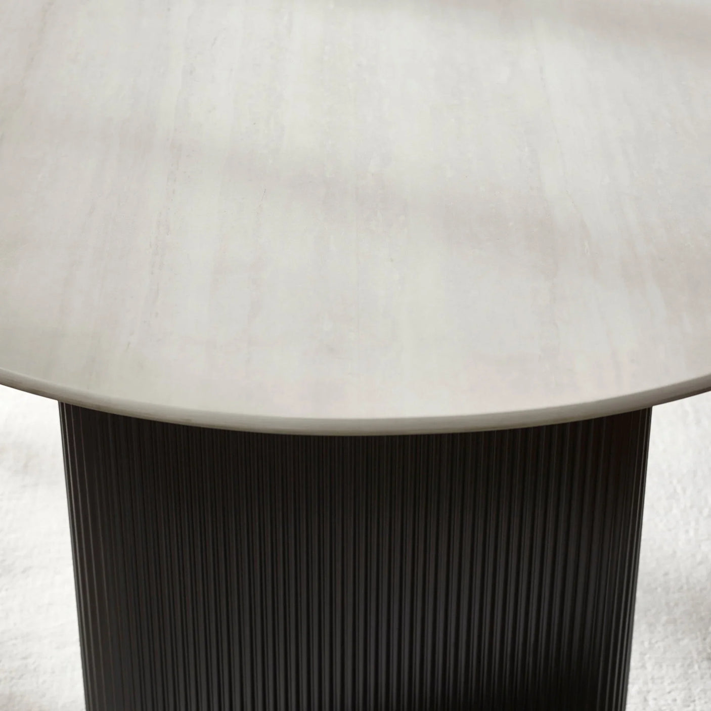 Round dining table with grey stone top and black ribbed cylindrical base