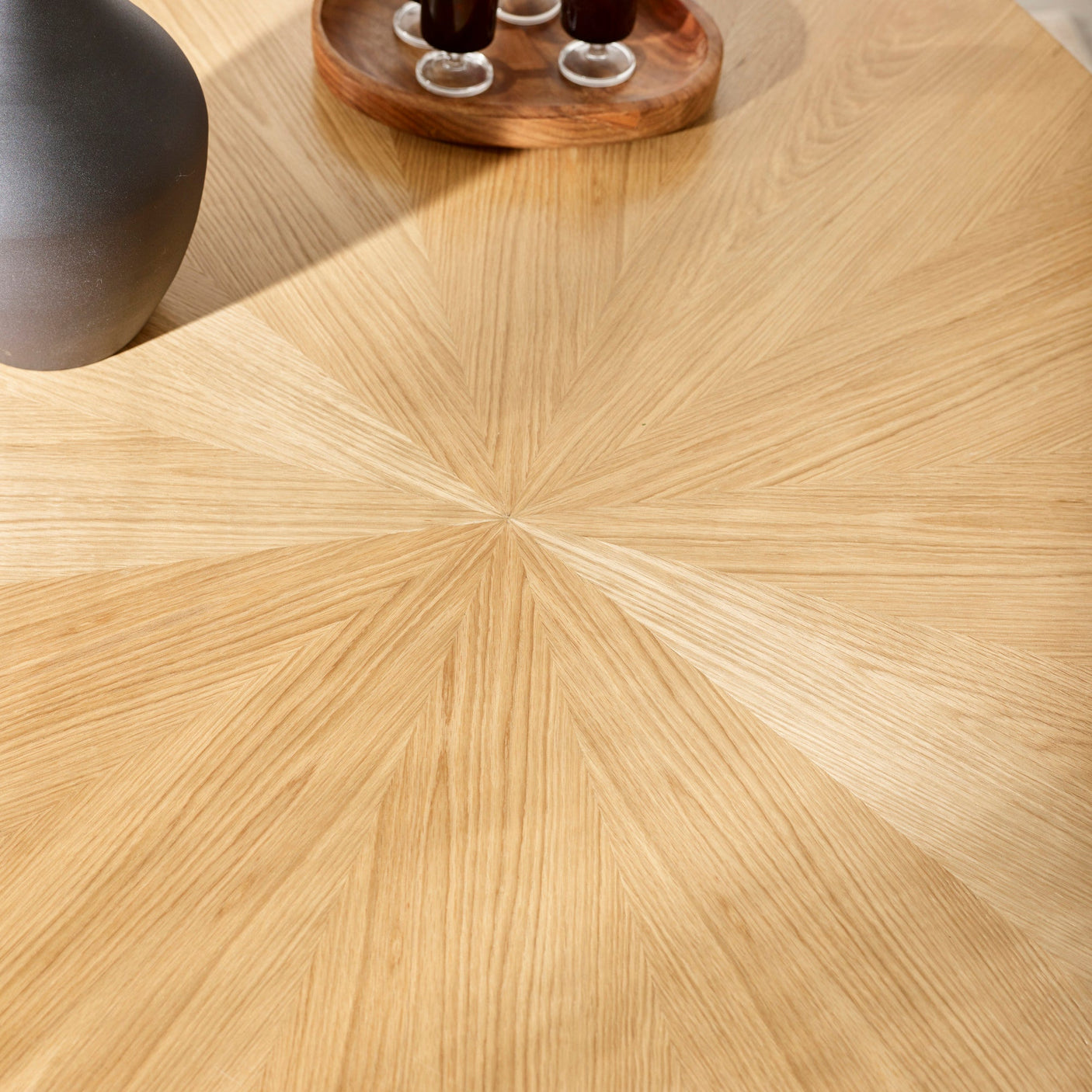 Close-up of light wood dining table surface showing radial wood grain pattern