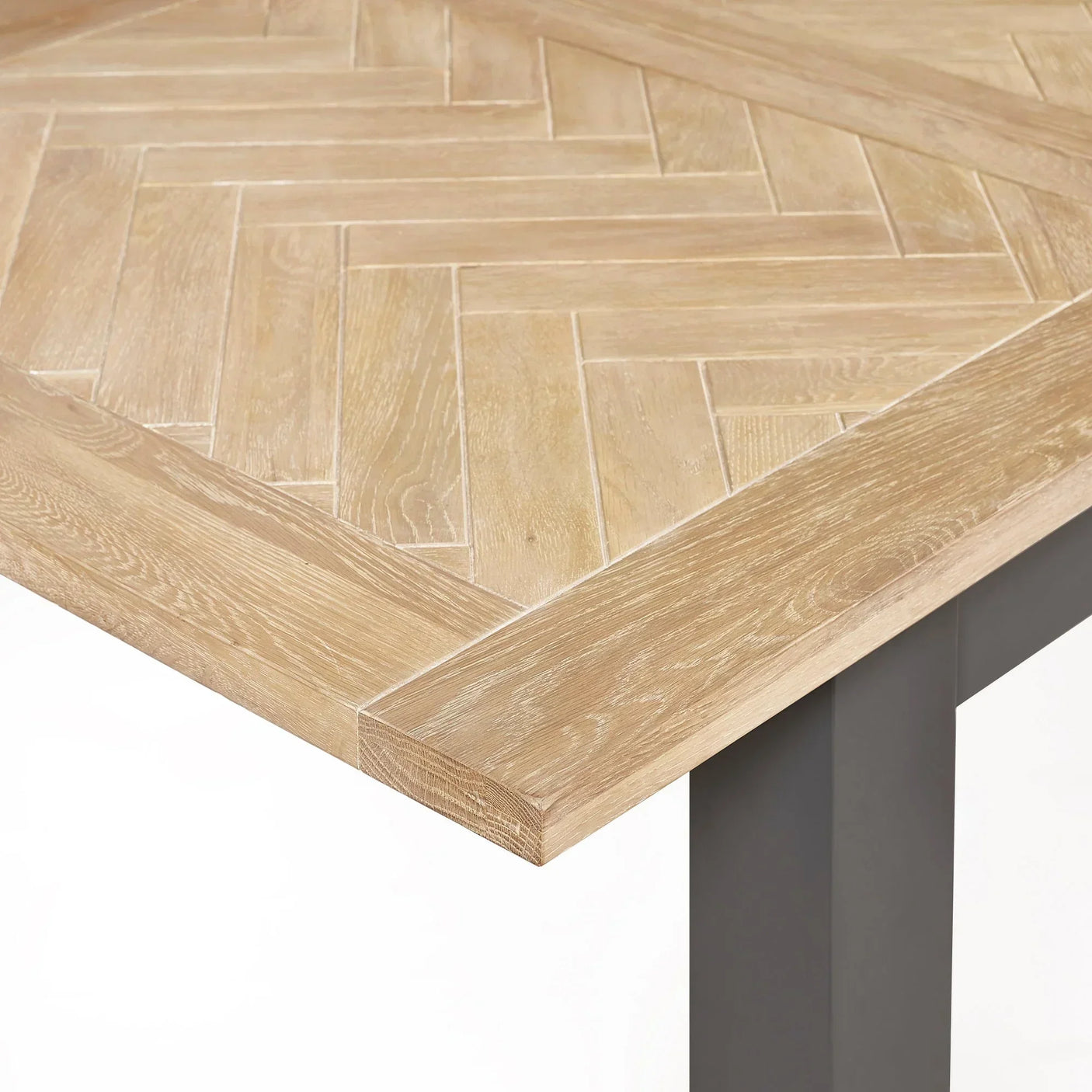 Light oak extending dining table corner with herringbone pattern top and dark legs