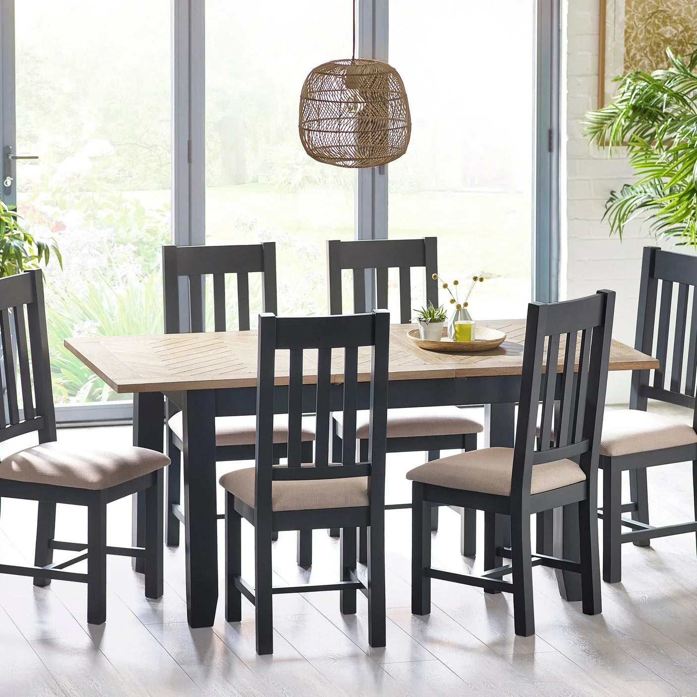 Bordeaux extending dining table with six black chairs in bright dining room