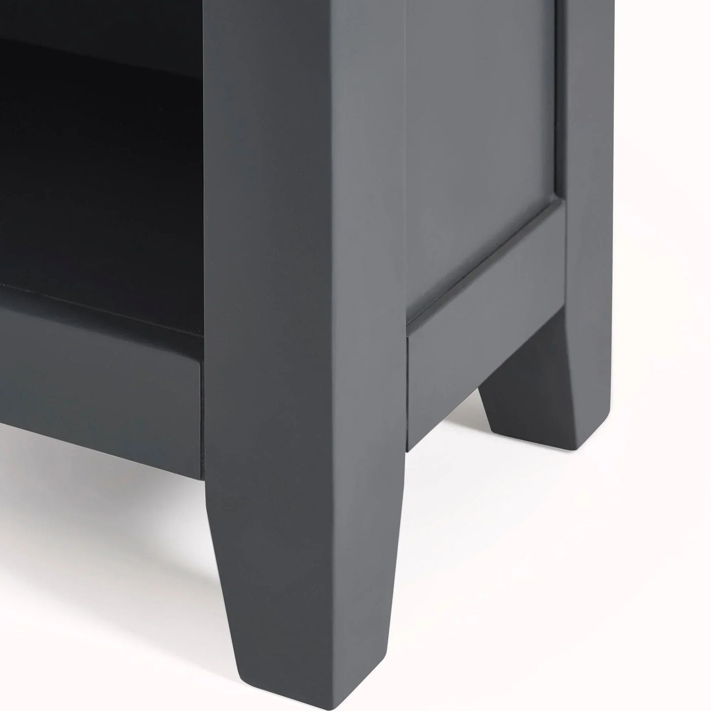 Close-up of dark grey wooden furniture leg and lower shelf detail