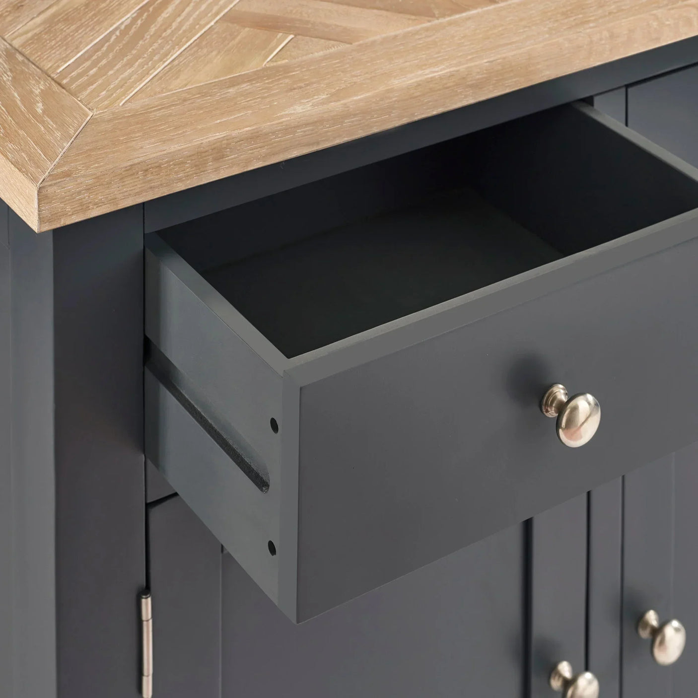 Closeup of dark grey sideboard drawer with brushed metal knob and oak effect top