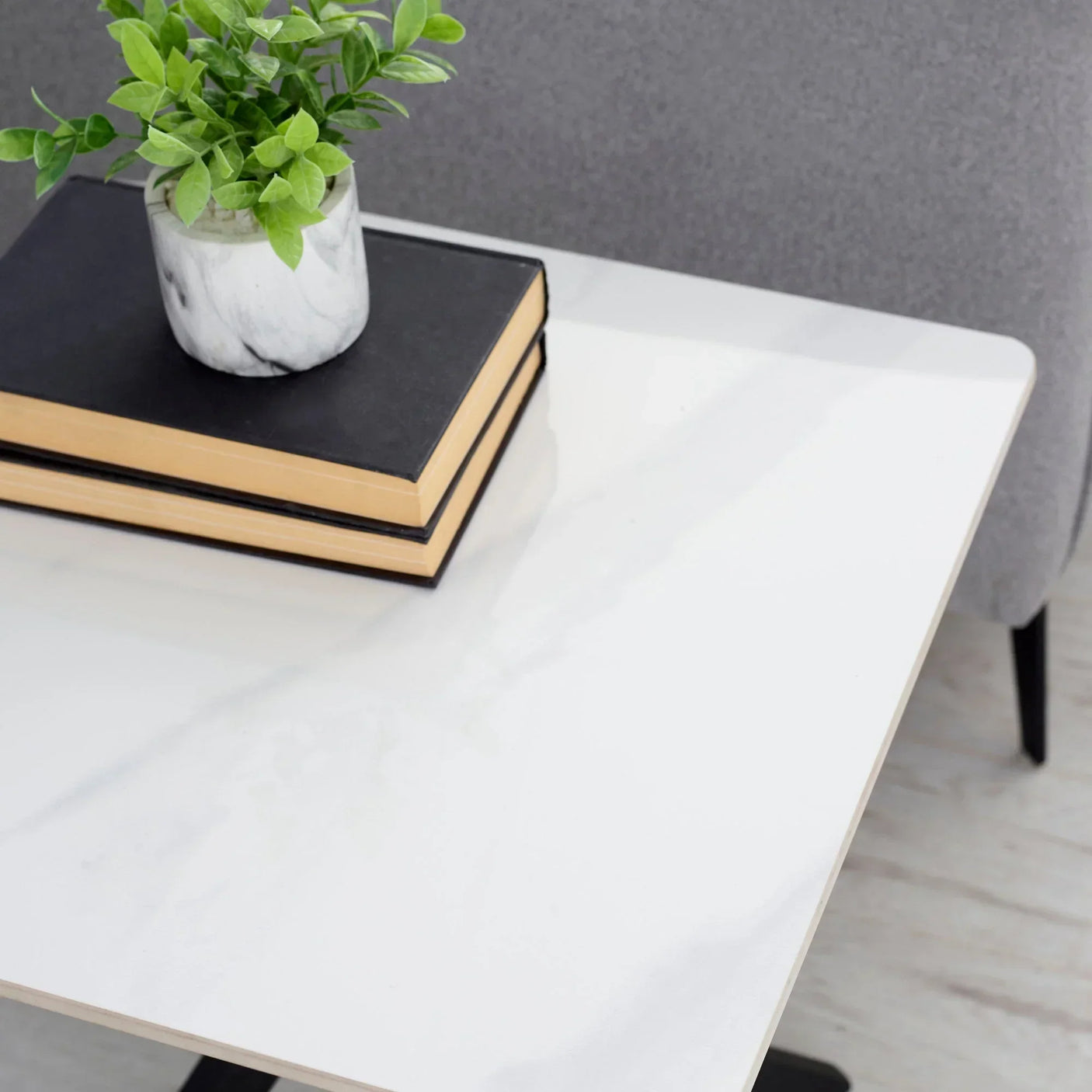 White marble lamp table detail with books and plant in marble pot