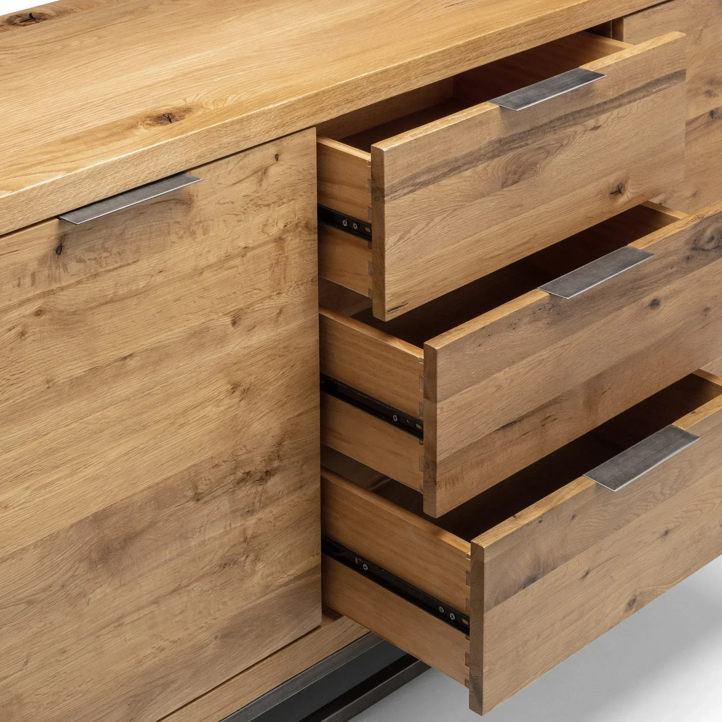Oak sideboard with metal handles and three open drawers, showcasing wood grain detail