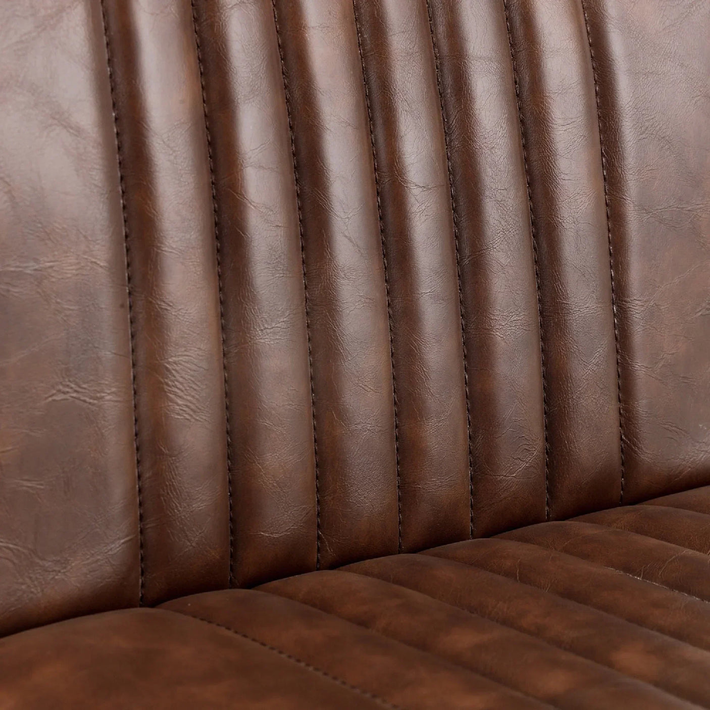 Close view of brown bar stool seat with vertical stitched faux leather upholstery