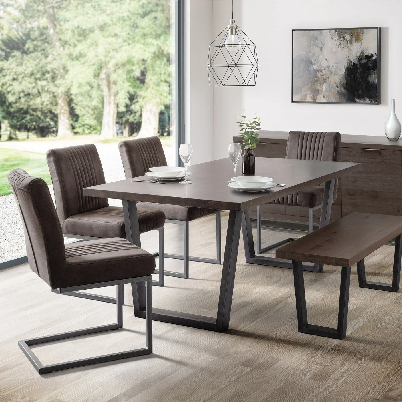 Dark oak dining table with modern metal legs, matching bench and chairs in a bright room