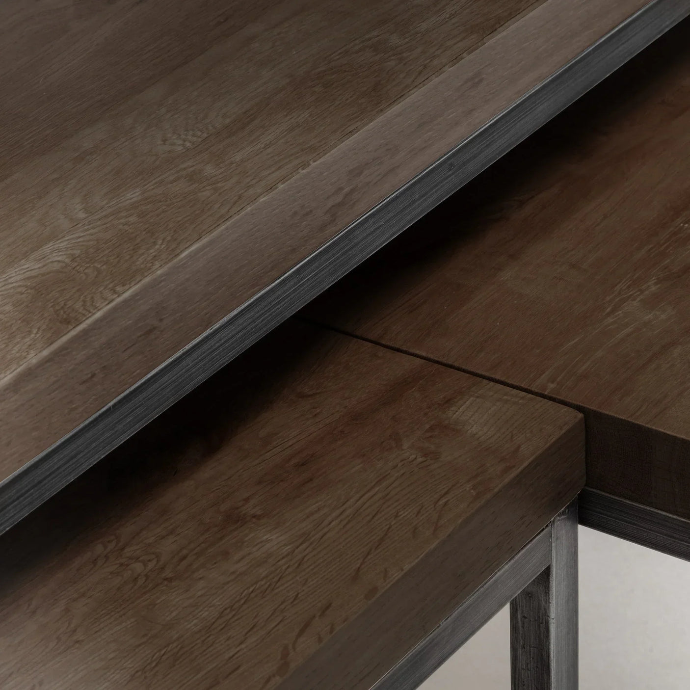 Closeup of dark oak nesting coffee tables showing wood grain and metal frame details