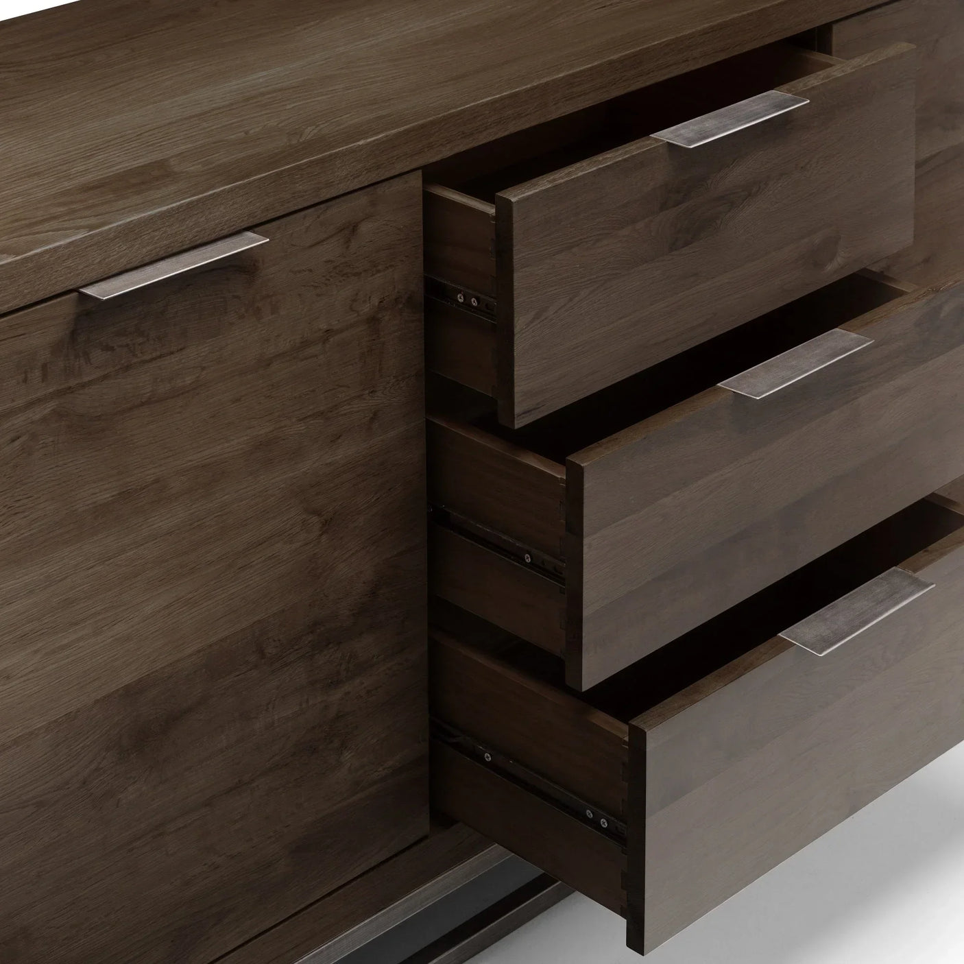 Dark oak sideboard with three open drawers and metal handles, close-up detail view