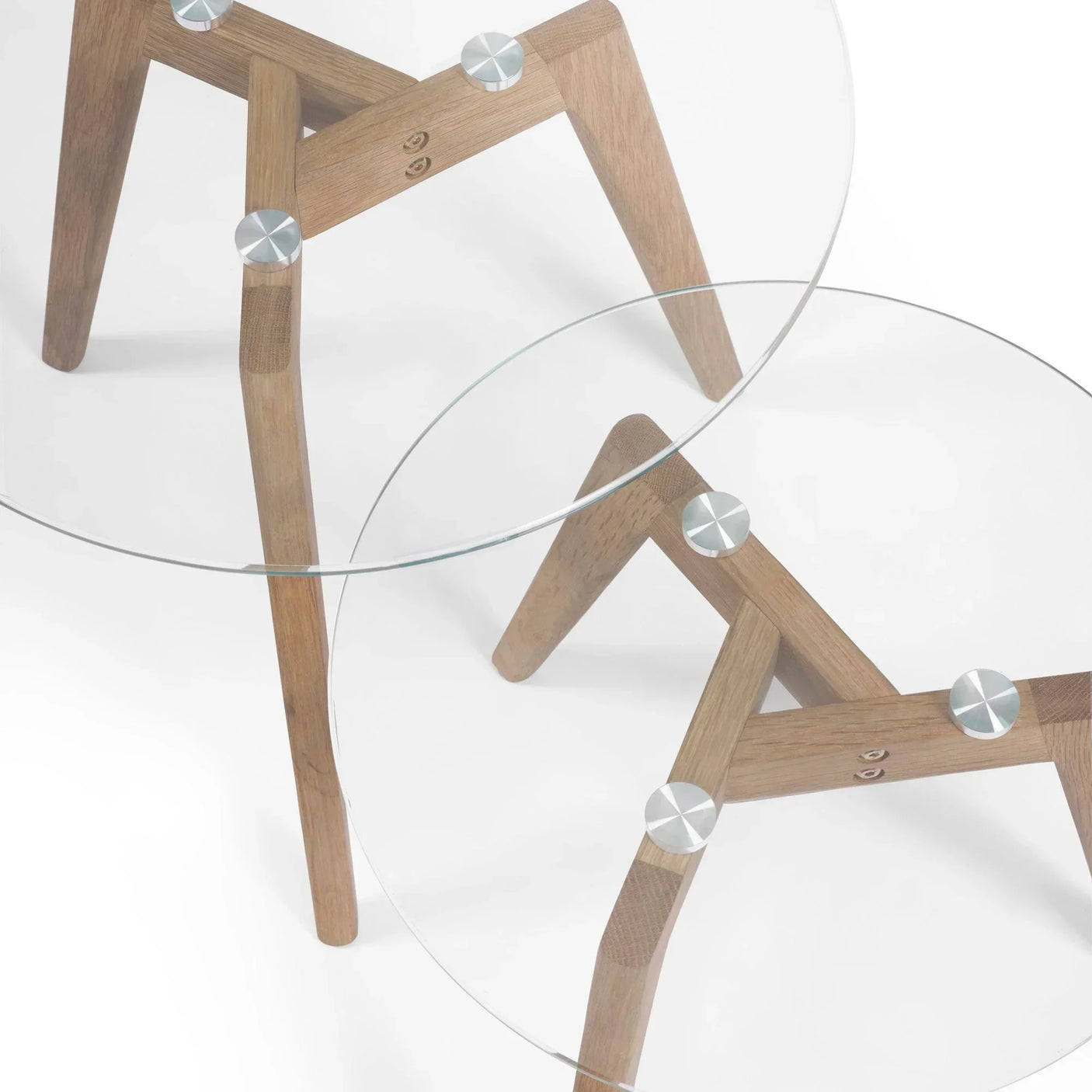 Round glass nest of tables with oak legs and metal fixings, close-up top view