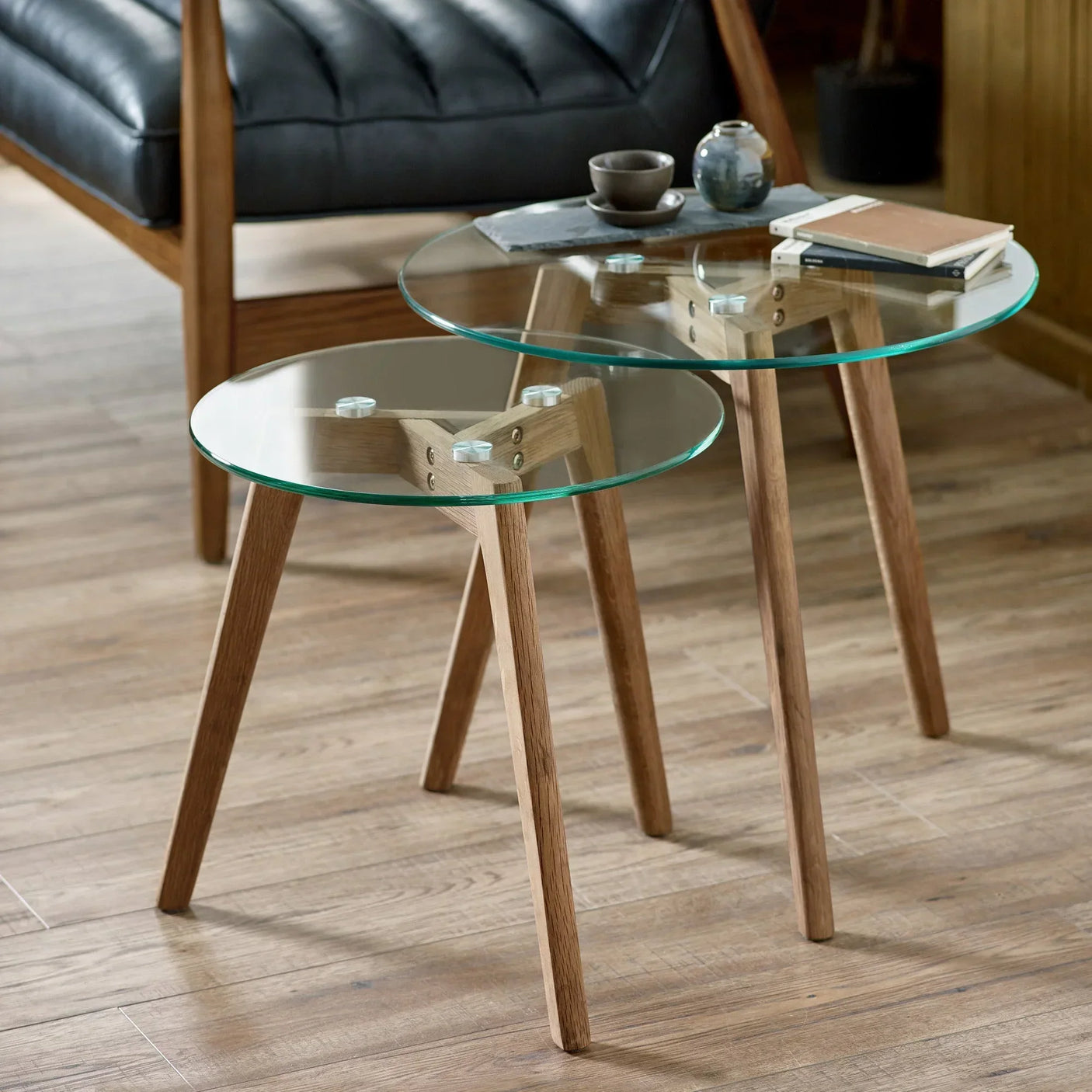 Glass nest of tables with oak legs in modern living room setting on wood floor
