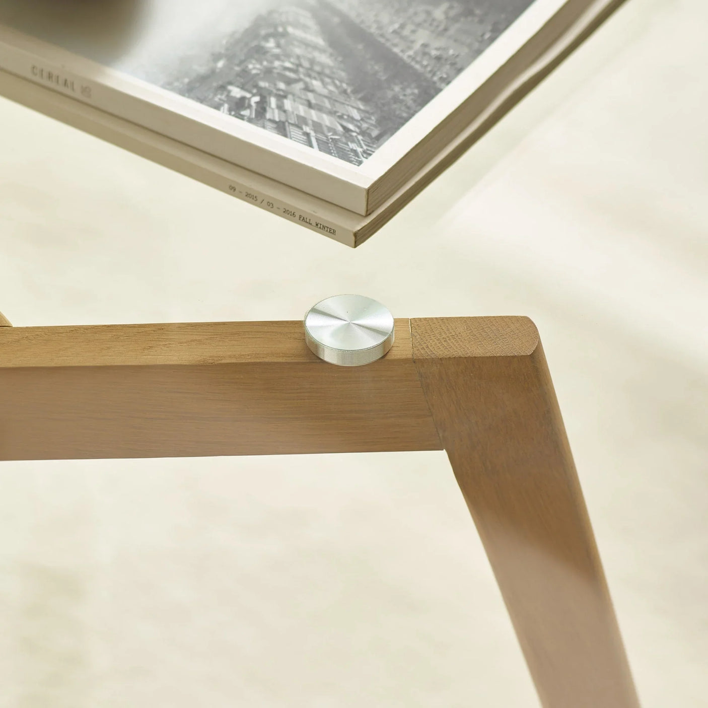 Glass coffee table with oak wood frame and silver metal fixing, close-up corner view