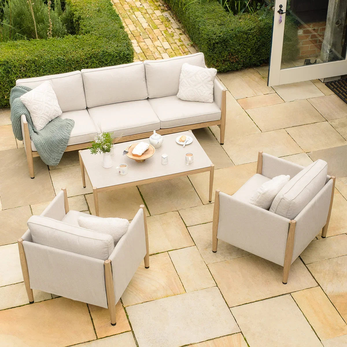 Cream outdoor garden furniture set with sofa, armchairs, and coffee table on stone patio