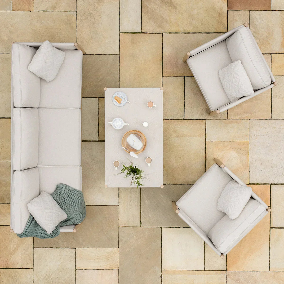Cream outdoor garden sofa set with chairs and coffee table on stone patio