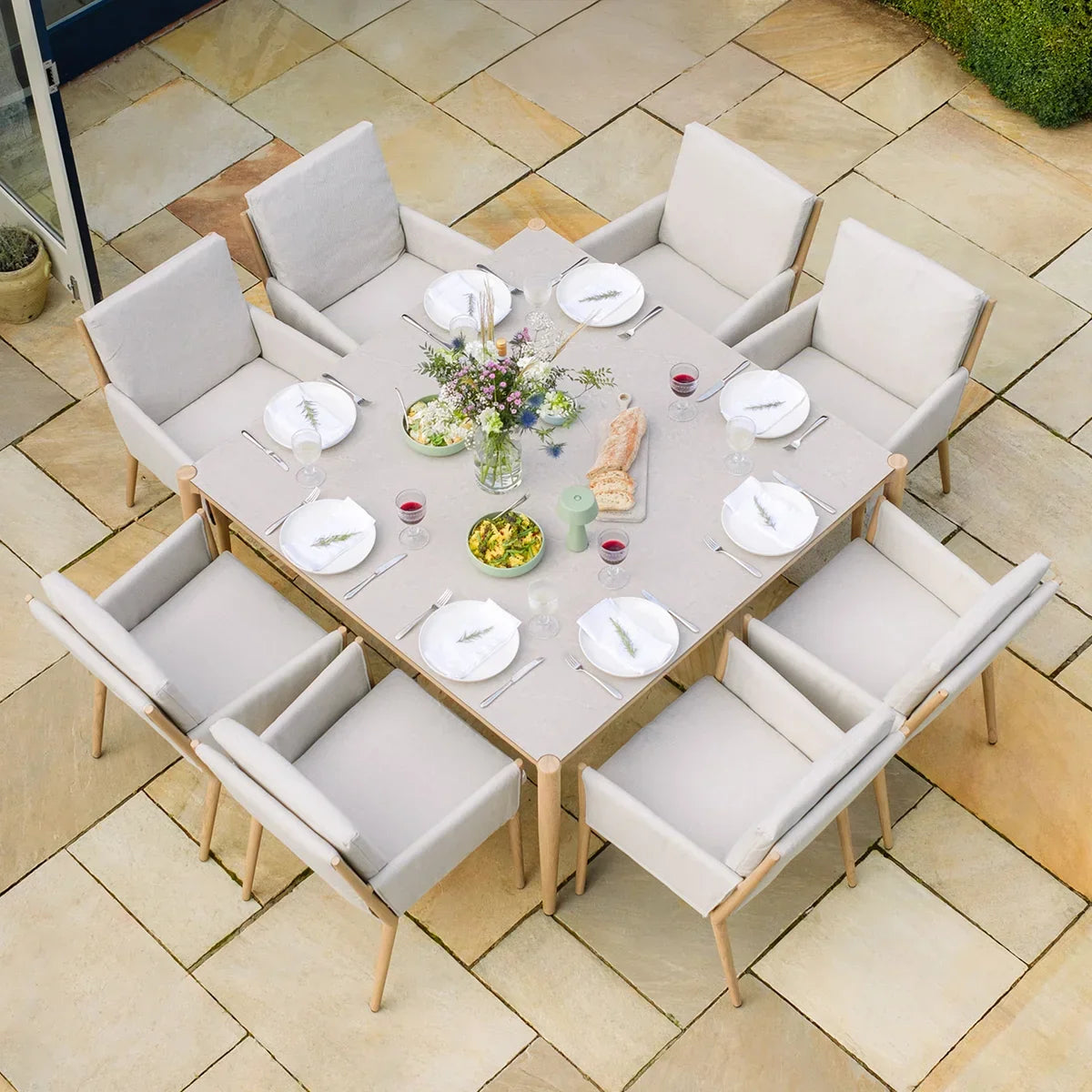 Outdoor dining set with eight cushioned chairs and square table set for a meal