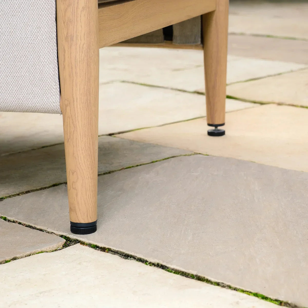 Close-up of wooden sofa legs on light outdoor patio tiles