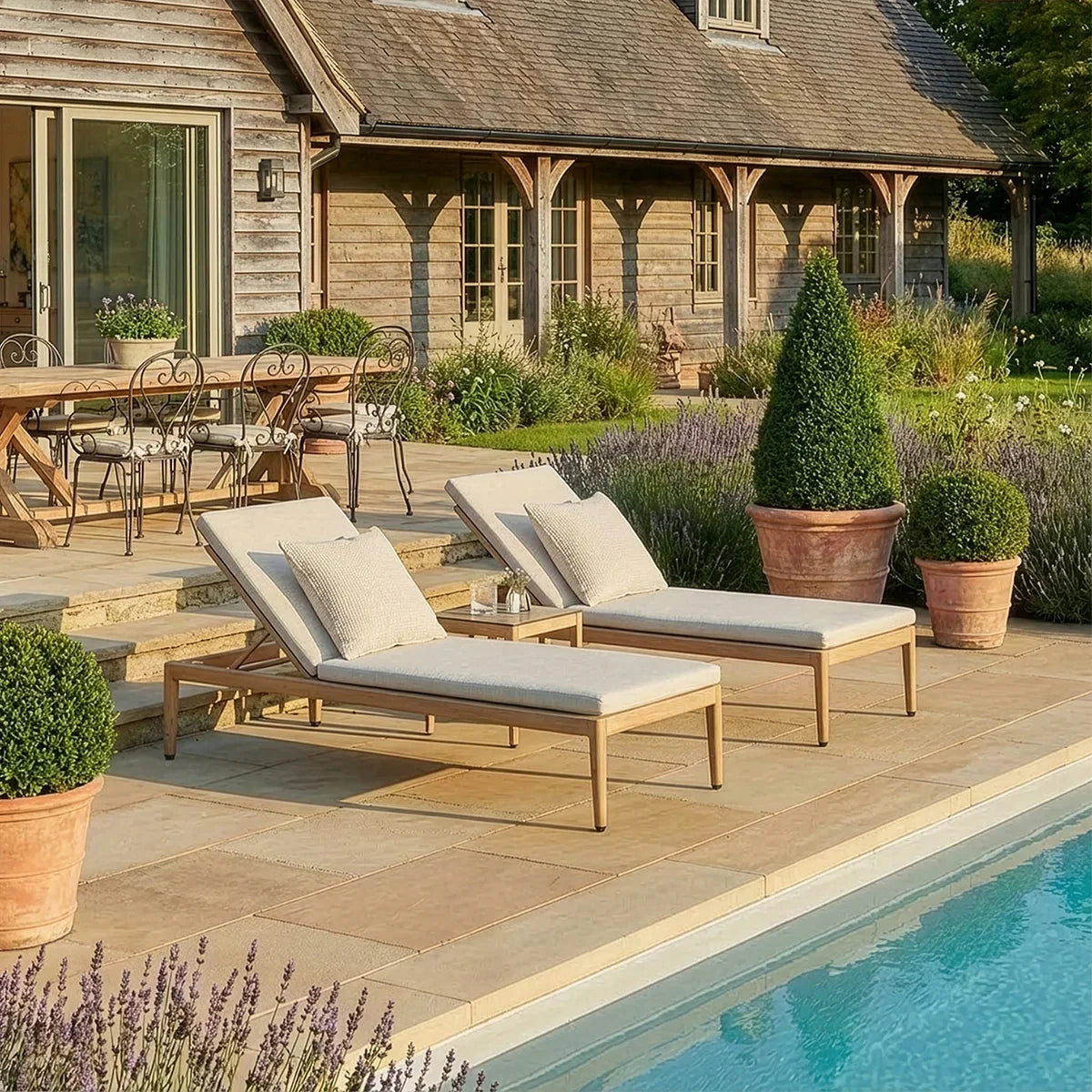 Outdoor sun loungers with light cushions by the pool on a stone patio