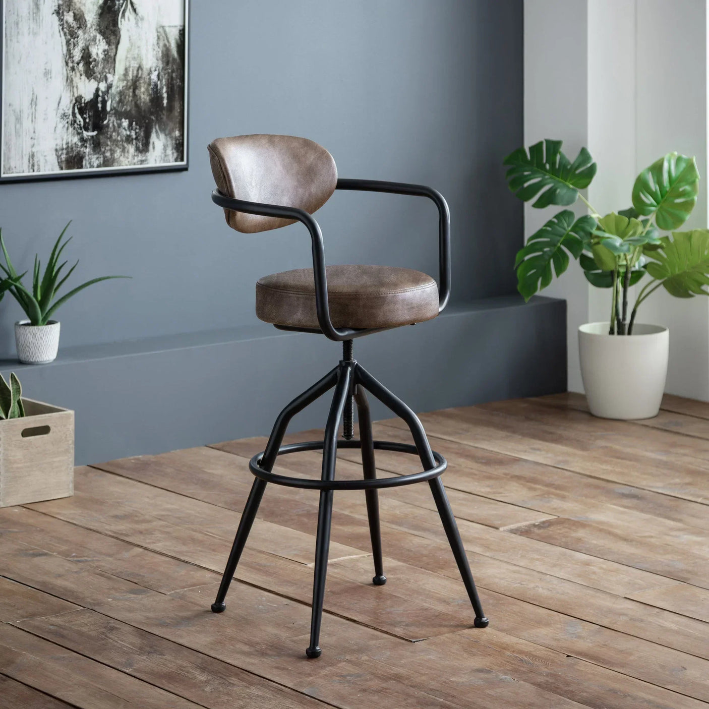 Brown leather bar stool with black metal legs on wooden floor in modern room