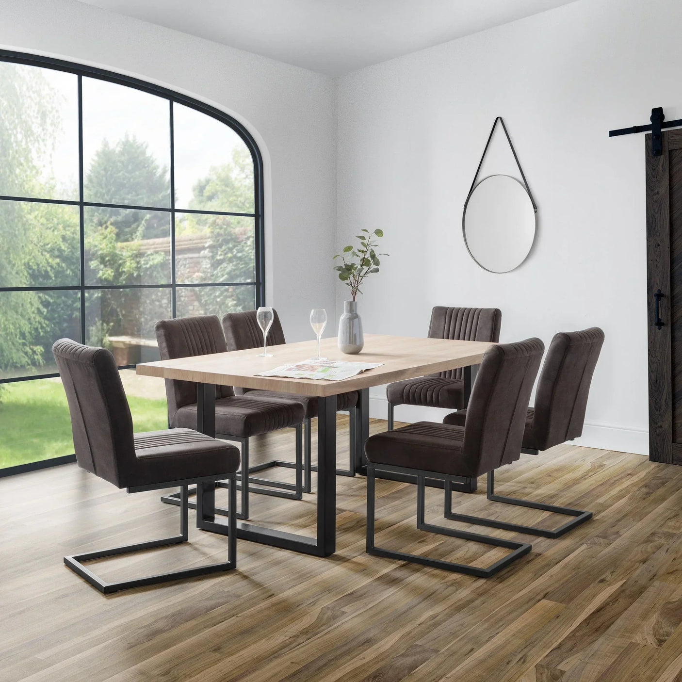 Rectangular dining table with black metal legs and six charcoal chairs in modern dining room